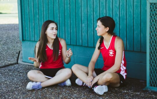 woman in red Nike tank top sitting beside woman in red tank top